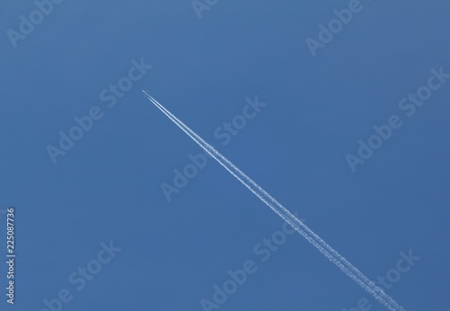 Plane flying on a blue sky, condensation line.