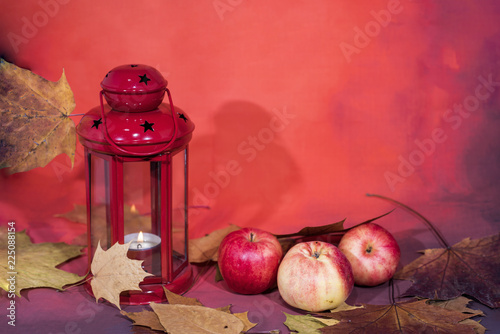 Red lantern lamp with candle and apples on red background photo