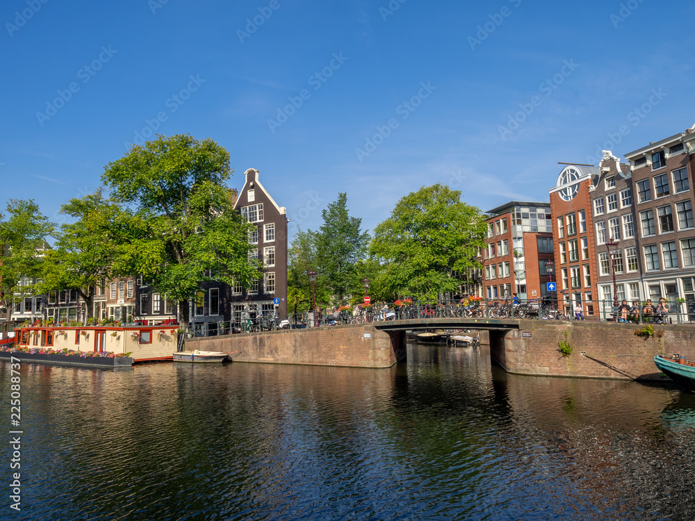 Naklejka premium Buildings and boats along Amsterdam's beautiful canals in central Amsterdam during the day. The canals are one of Amsterdam's main attractions.