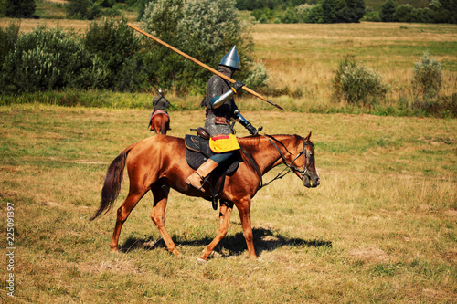 Medieval armored equestrian soldiers with lances on horses