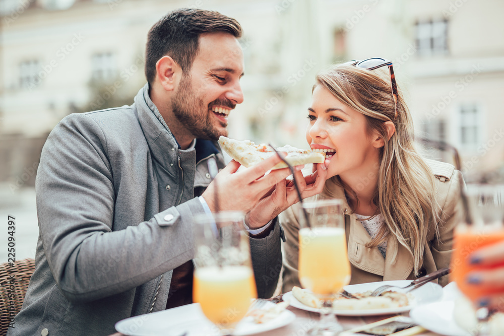 Beautiful loving couple sitting in outdoor cafe and eating pizza. Lifestyle concept Beautiful loving couple sitting in outdoor cafe and eating pizza. Lifestyle concept
