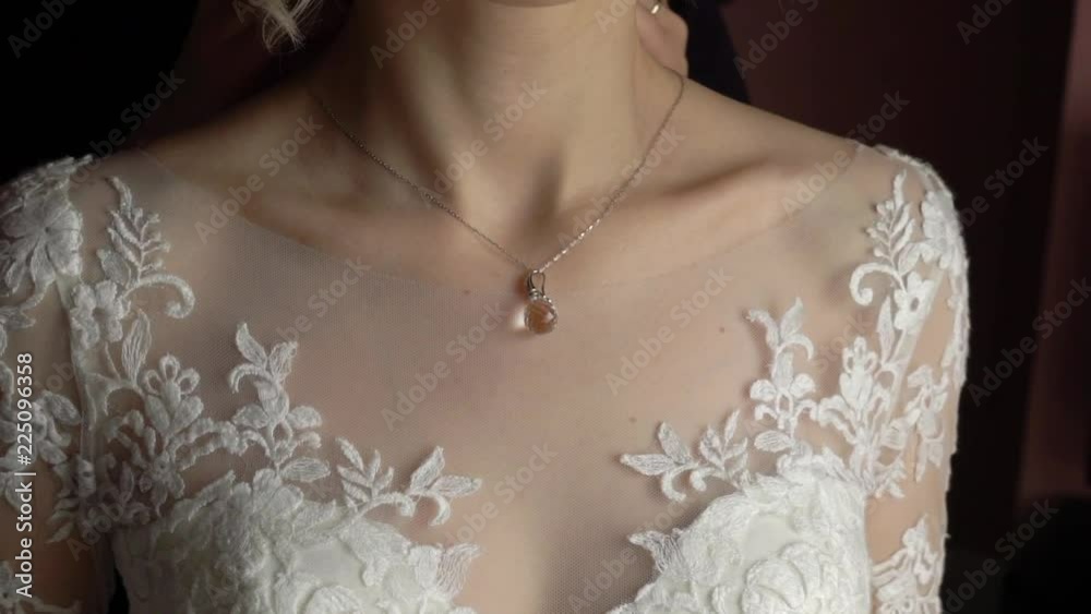 Wedding. Jewelry. The bride in a white dress putting on a necklace around her neck slowmotion Wedding. Jewelry. The bride in a white dress putting on a necklace around her neck slowmotion