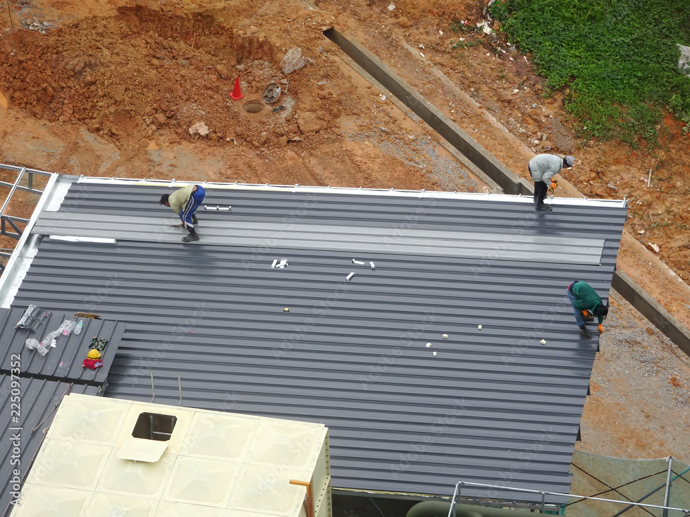 Installation of metal deck roof sheet by construction workers. Complete ...