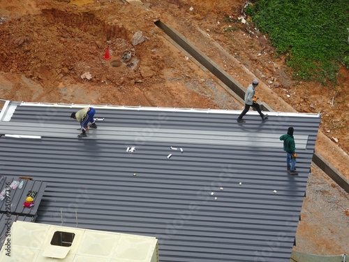 Installation of metal deck roof sheet by construction workers. Complete with roof insulation and heat reflector sheet. photo