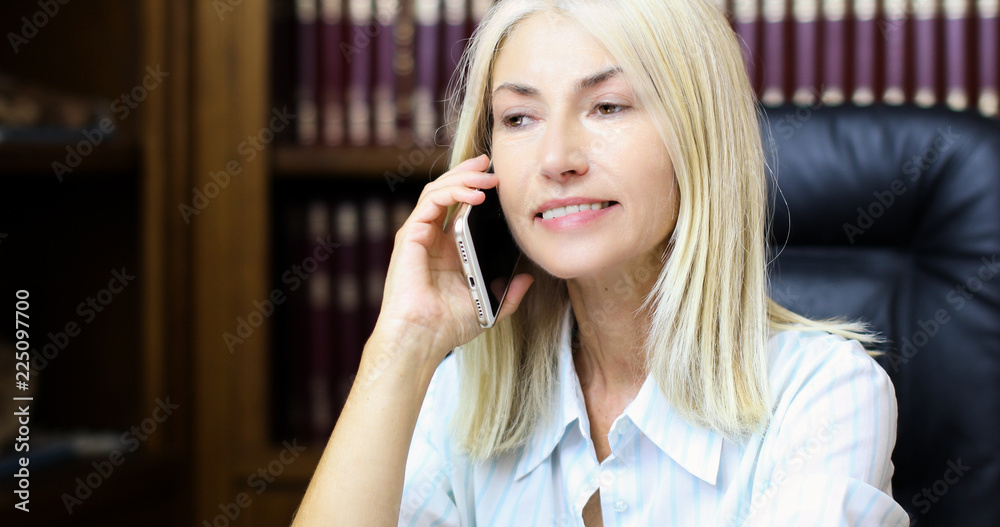 Mature secretary talking on the phone and smiling Mature secretary talking on the phone and smiling