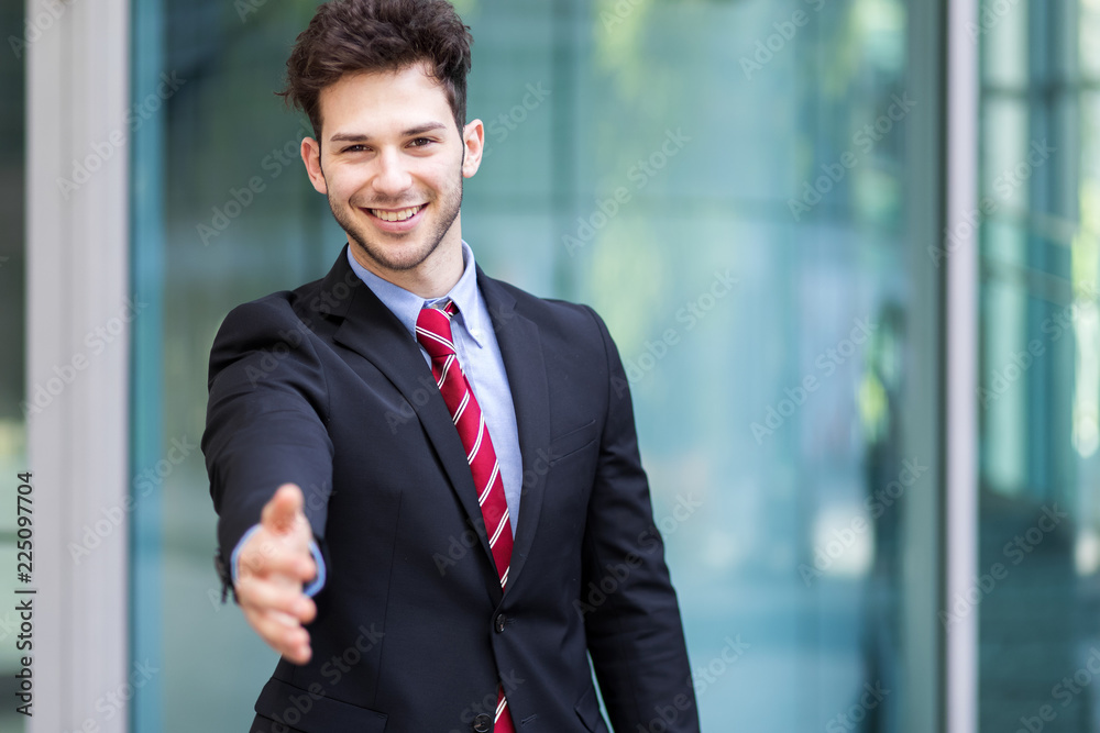 Handsome businessman offering handshake in an urban setting Handsome businessman offering handshake in an urban setting