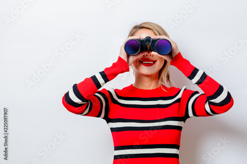 Portrait of a beautiful white woman in red sweater with binocular on white background, isolated.