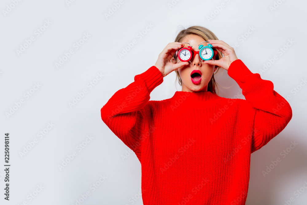 Portrait of a beautiful white woman in red sweater with little alarm clocks on white background, isolated. Portrait of a beautiful white woman in red sweater with little alarm clocks on white background, isolated.