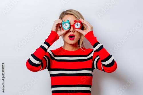 Portrait of a beautiful white woman in red sweater with little alarm clocks on white background, isolated.