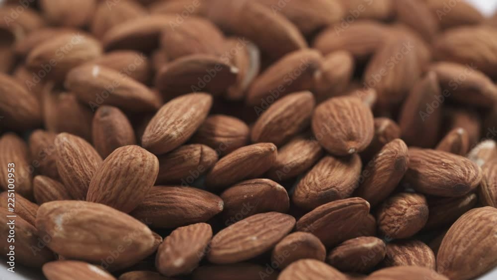 closeup roasted almonds falling in white bowl closeup roasted almonds falling in white bowl