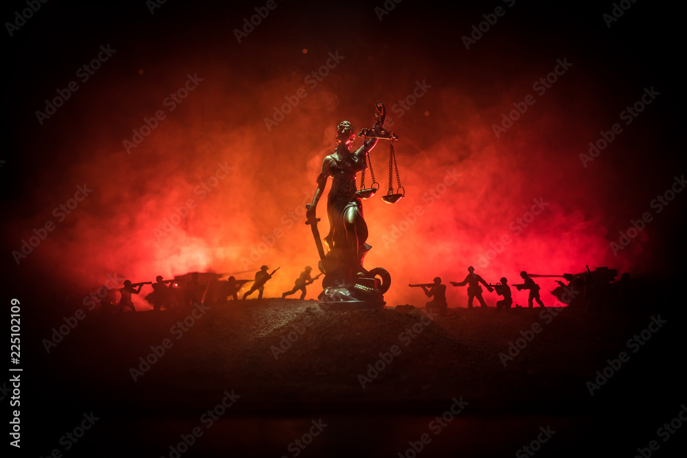 War - no justice concept. Military silhouettes fighting scene and The Statue of Justice on a dark toned foggy background.