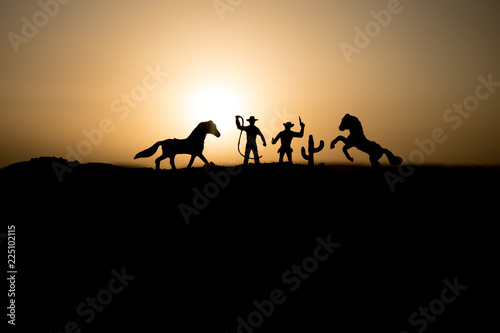 Cowboy concept. Silhouette of Cowboys at sunset time. Cowboys silhouettes on a hill with horses.
