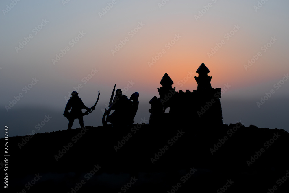 Medieval battle scene on sunset. Silhouettes of fighting warriors on sunset background.