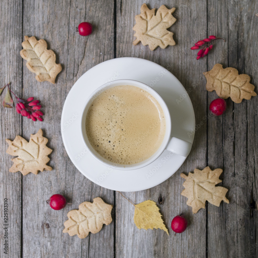Cup of hot coffee, cookies in form leaves, dry autumn leaves, hawthorn and barberry fruits on a wooden background. Top view, flat lay Cup of hot coffee, cookies in form leaves, dry autumn leaves, hawthorn and barberry fruits on a wooden background. Top view, flat lay