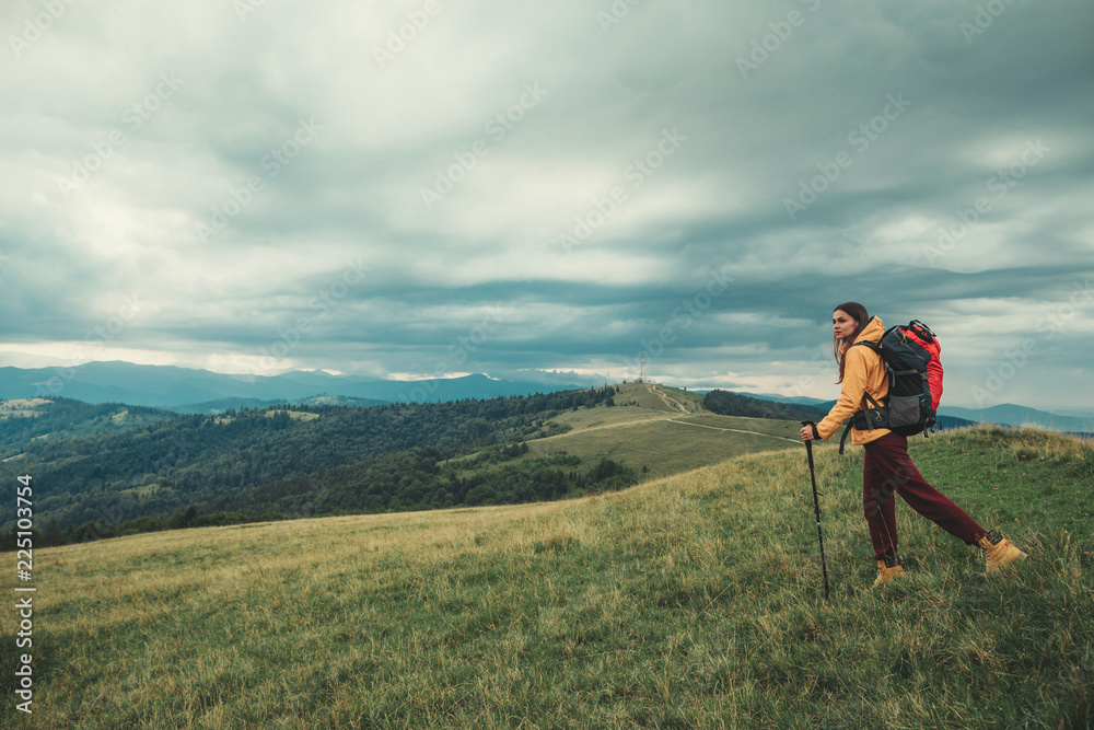 Fototapeta premium Pleasant young woman walking in the mountains while using Nordic walking sticks