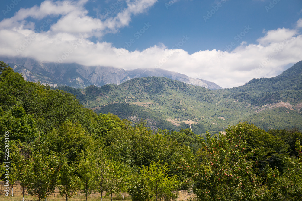 Majestic landscape of the mountains and forest in Caucasus at summer. Dramatic sky with clouds.