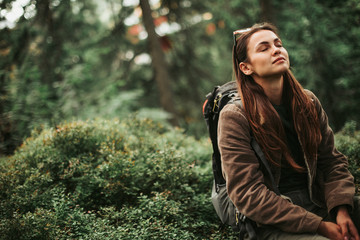 I feel healing energy. Portrait of serene girl with closed eyes enjoying atmosphere of coniferous wood
