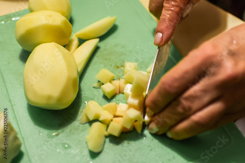 Woman's hands with knife cutting potato