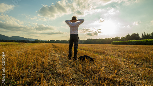 Businessman standing relaxed in harvested field