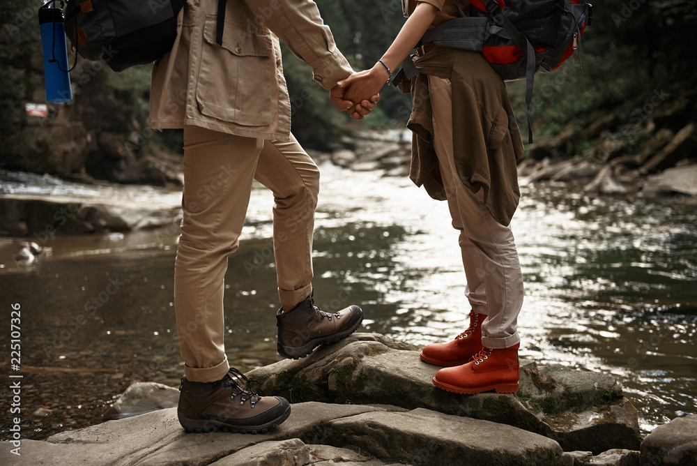 Romantic moment. Close up of beautiful active couple of hikers standing in front of each other and holding hands Romantic moment. Close up of beautiful active couple of hikers standing in front of each other and holding hands