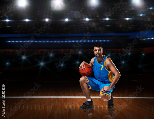 basketball player in blue uniform sitting on basketball court