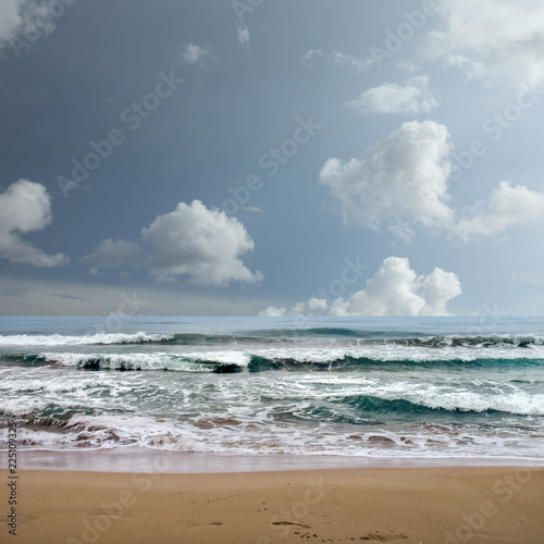 landscape image of sandy beach and waves over stormy sky
