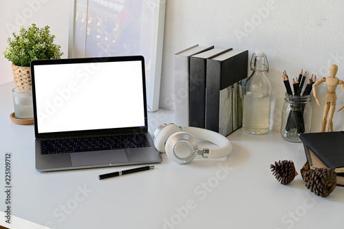 Creative workspace mock up laptop blank screen in modern home office interior with office supplies on white wooden desk,