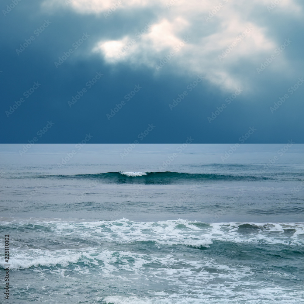 Seascape and waves over stormy sky