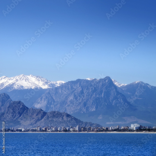 Antalya city with high mountains over clear blue sky.