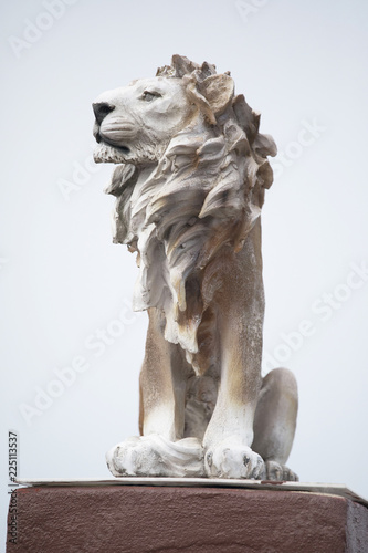 Ancient Sculpture of White sitting Coade stone Lion isolated on white backgrounds, clad strong statue, leadership symbol monument photo