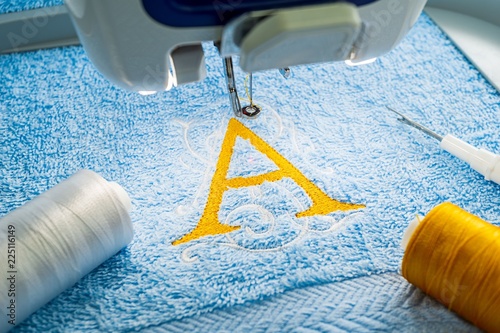 Alphabet logo design on towel in hoop of embroidery machine photo