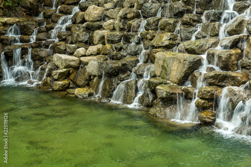 small waterfall rushing down a rocky dam in the park