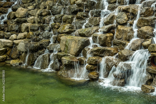 small waterfall rushing down a rocky dam in the park