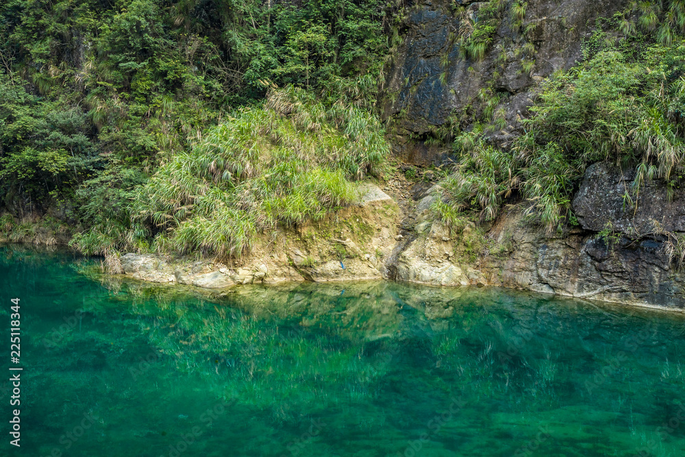 Naklejka premium clear green water in the creek at the bottom of a cliff