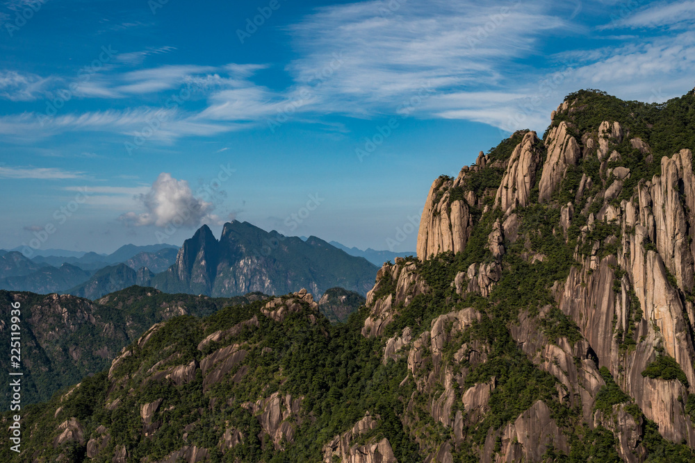 green forest covered mount sanqing peaks under the cloudy blue sky