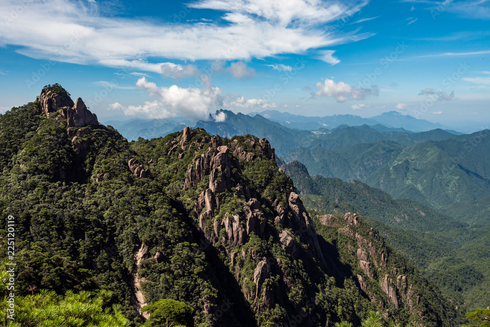 green forest covered mount sanqing valley under the cloudy blue sky