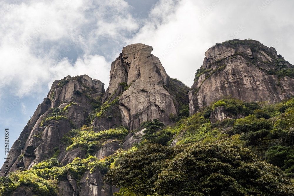 unique rock formation covered with forest on the three peaks of Mount Sanqing under the cloudy blue sky