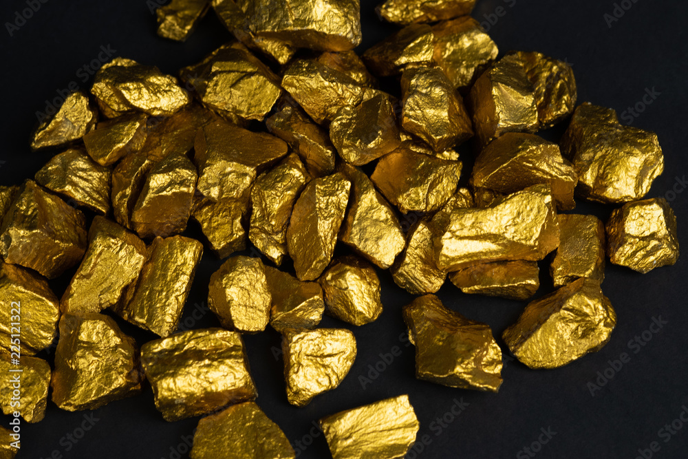 A pile of gold nuggets or gold ore on black background, precious stone or lump of golden stone, financial and business concept.