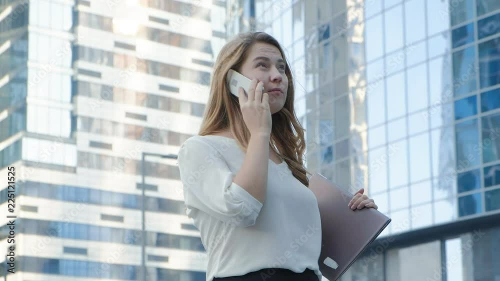 Young business woman talking is using smartphone in city park business center Young business woman talking is using smartphone in city park business center