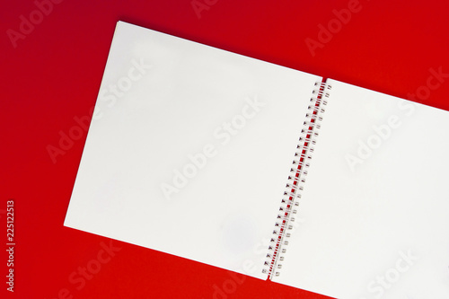 close up of open notebook on spring lying on red background