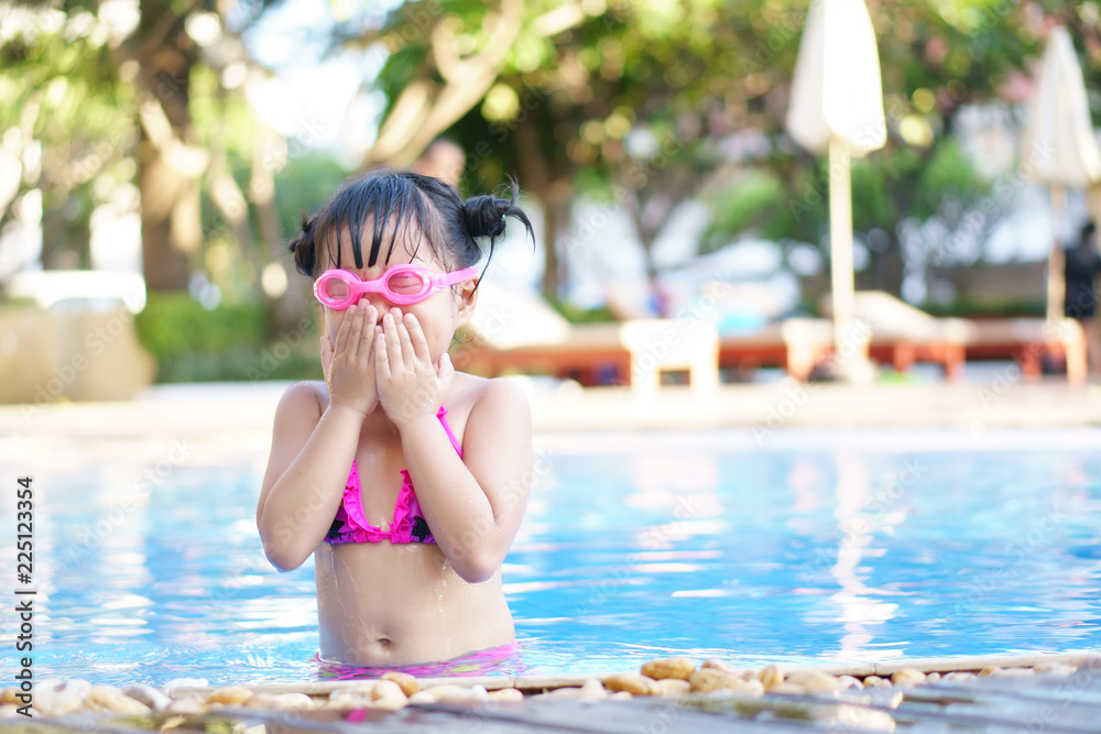 Asian child cute or kid girl wear pink bikini and goggles for swimming and  choke water