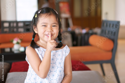 Billede på lærred Asian child cute or kid girl smile with laugh squat and forefinger close mouth f