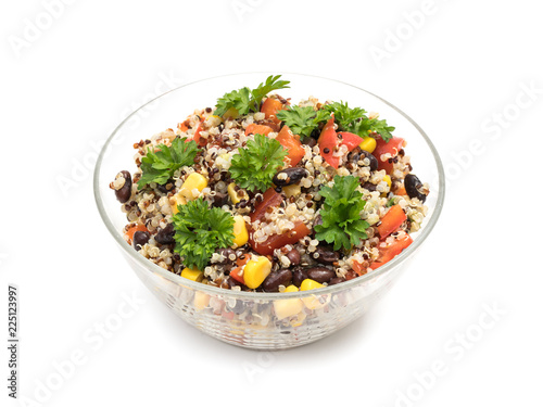 Glass bowl with quinoa salad with red pepper, corn, tomato and black beans, topped with parsley and isolated on white background