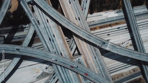 Drone ascending and spinning fast above large highway road intersection in Los Angeles with cars on multiple flyovers.