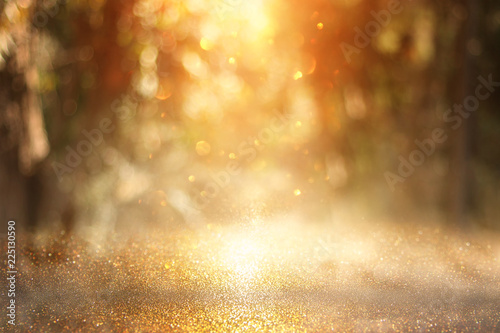 blurred abstract photo of light burst among trees and glitter golden bokeh lights.