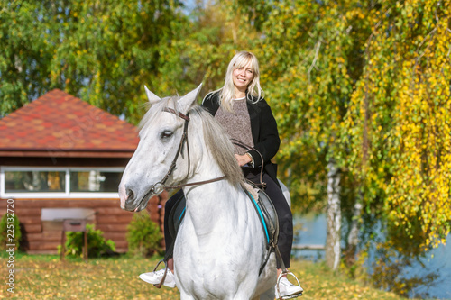Attractive young woman riding on horse rural location at autumn