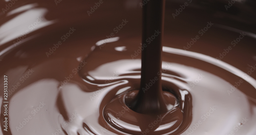 closeup pouring melted dark chocolate from spoon closeup pouring melted dark chocolate from spoon
