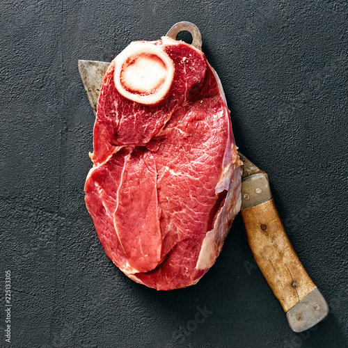 Piece fresh beef meat bone with butcher knife top view photo