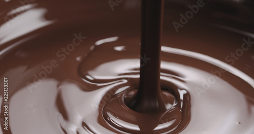 closeup pouring melted dark chocolate from spoon