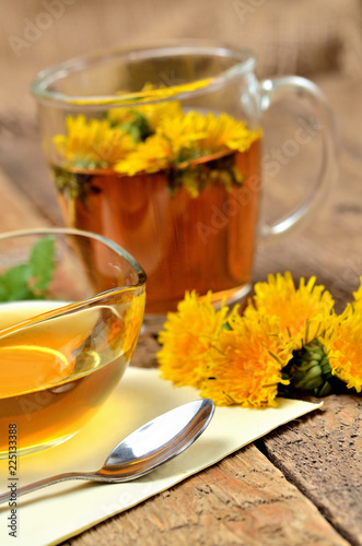 Herbal tea, dandelion honey, spoo and dandelion head around - vertical photo
